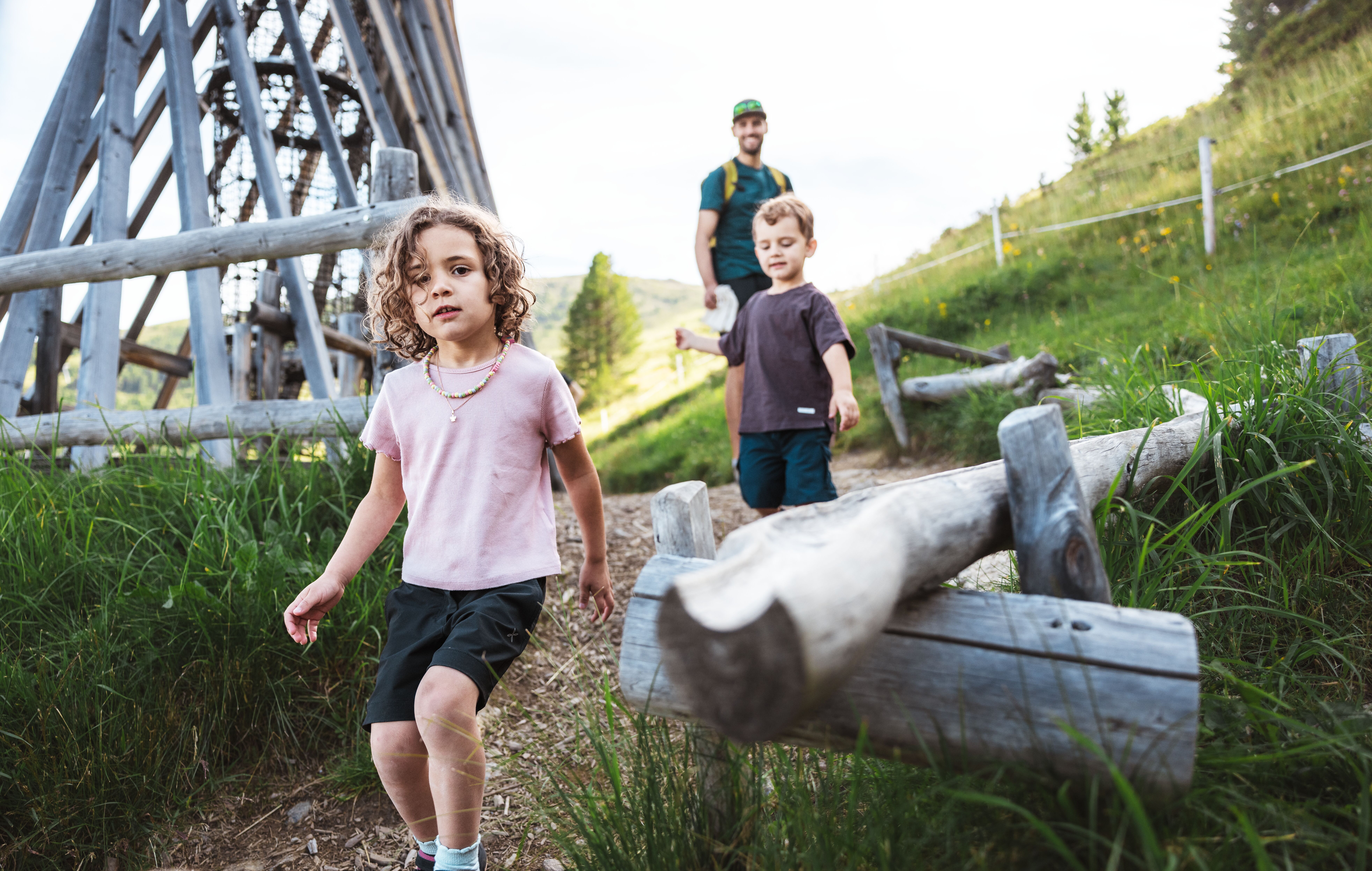 zwei kleine Kinder mit ihrem Vater im Zirbenpark, Abenteuerspielplatz aus Holz