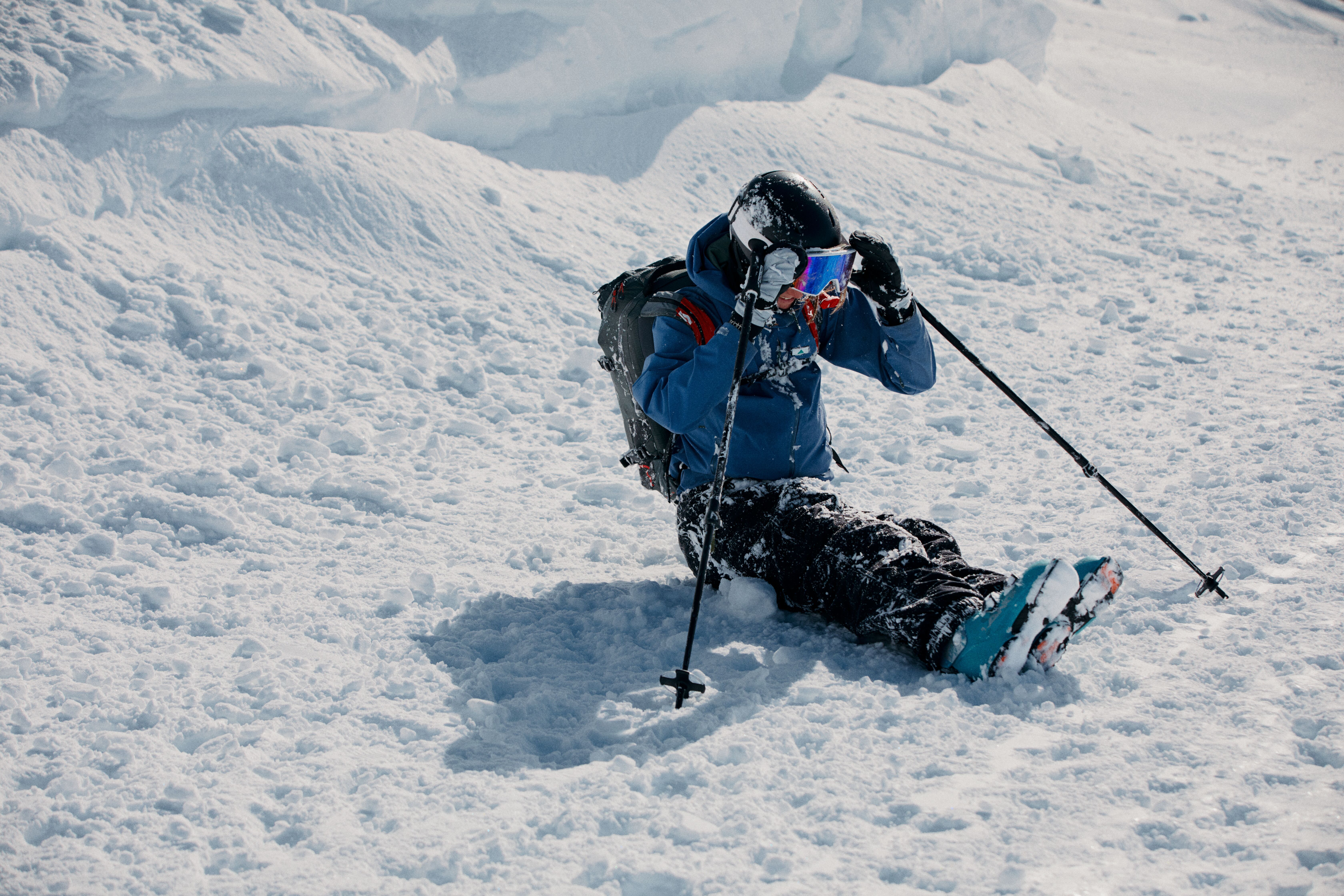 SKifahrer sitzt nach einem harmlosen Sturz schneebedeckt am Boden