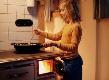 Vinzent keeps an eye on things as the meat slowly cooks on the wood-burning stove with its iron plate.